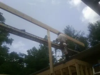 Carpenter setting a ridge beam over a new addition frame — Ice Dam Removal by Roofing Brothers in Jonesville