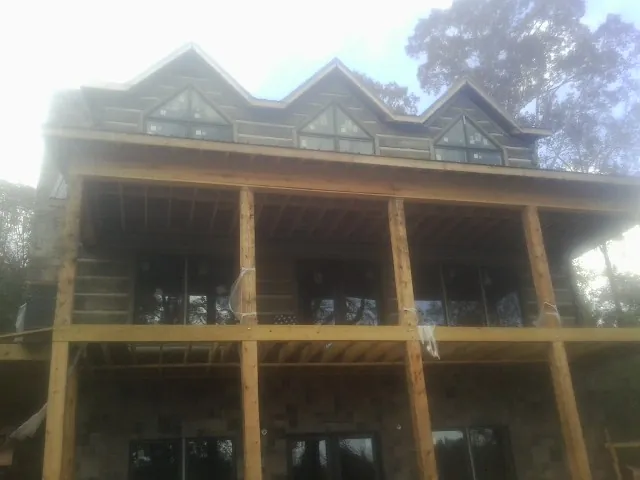 Dormers and porch framing on a large log home under construction — Roof Coating work by our crew in Jonesville