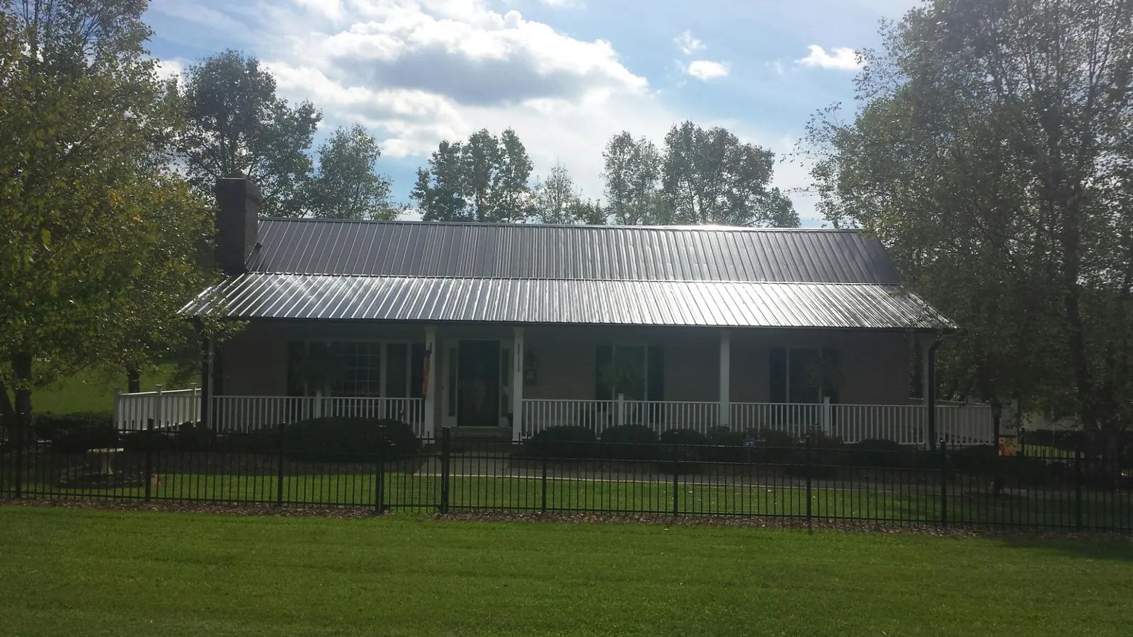 Gray metal roof on a brick ranch with a full width front porch — Gutter Guard Installation work by our crew in Jonesville