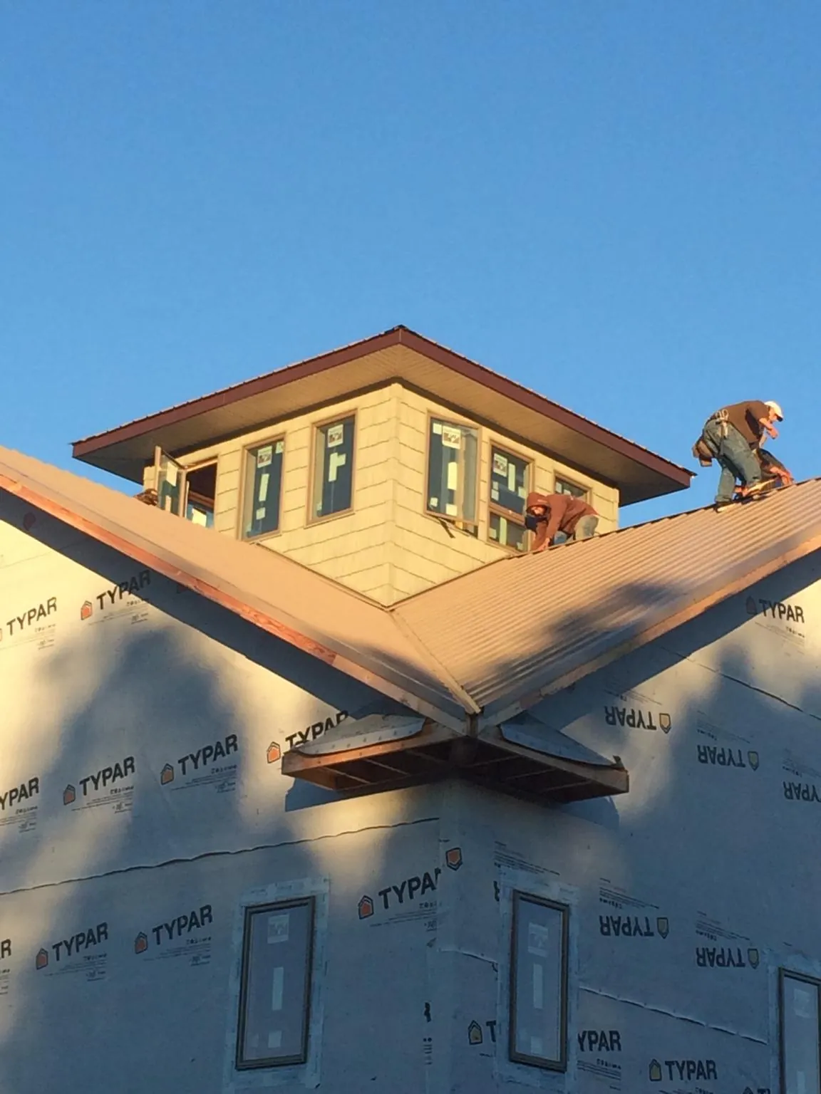 Roofers working around a rooftop cupola on a new metal roof at sunset — Roof Waterproofing in Jonesville by Roofing Brothers